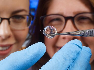 Researchers holding a single drop of water using a tool